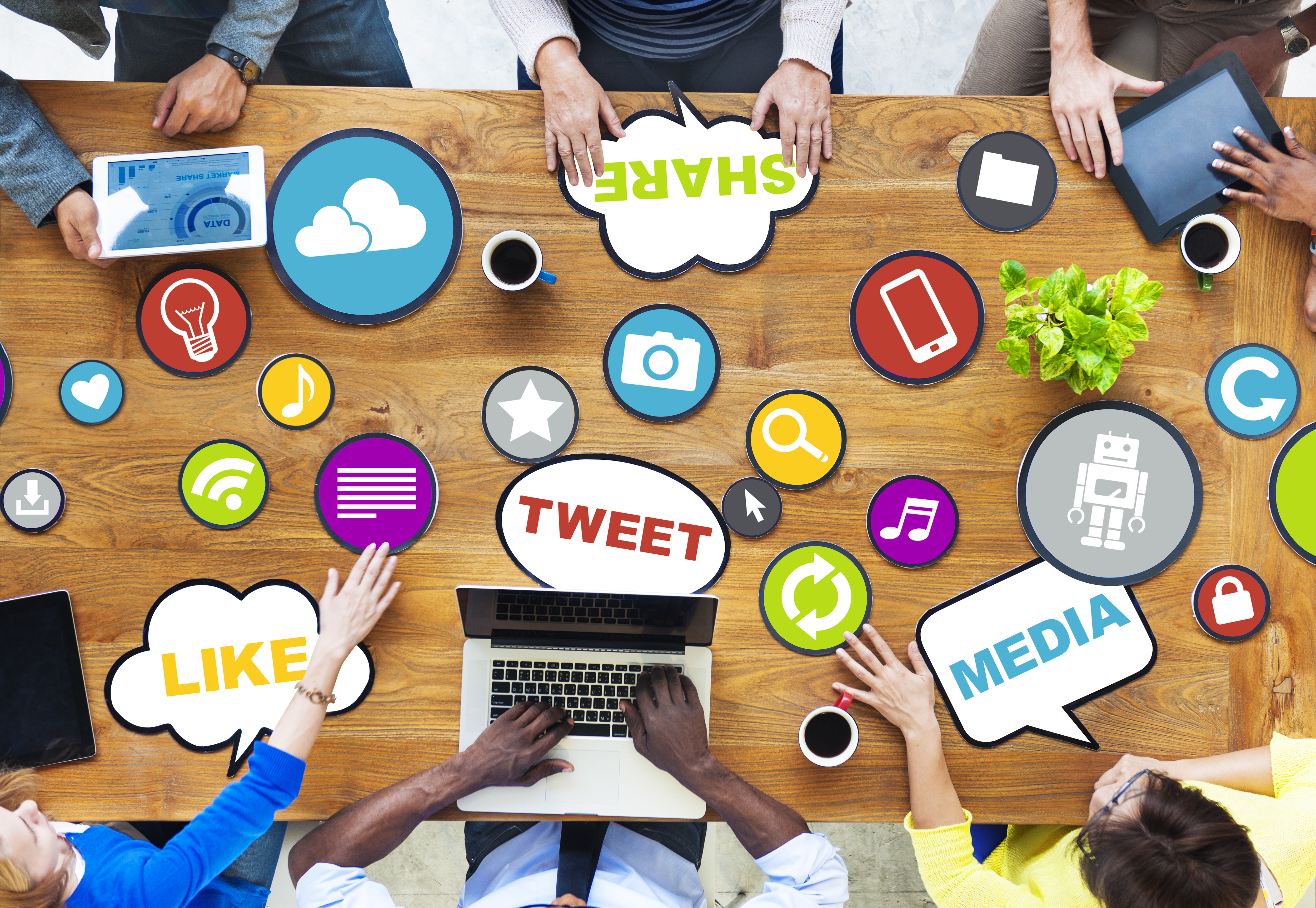 A table with people working that has social media-related words and logos on it